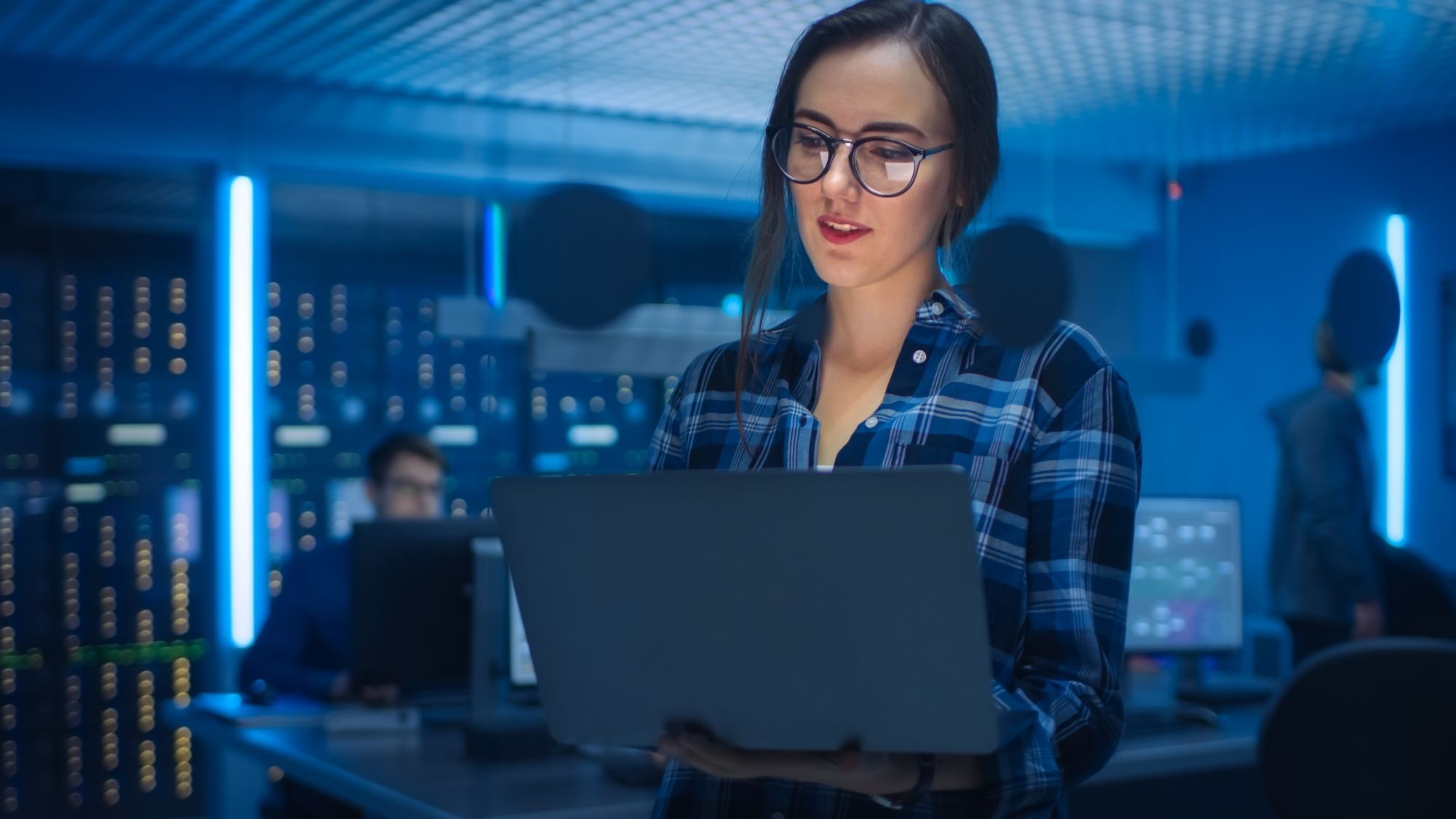 iso 27001-annex-a-dqs-mitarbeiterin schaut auf laptop in it umgebung