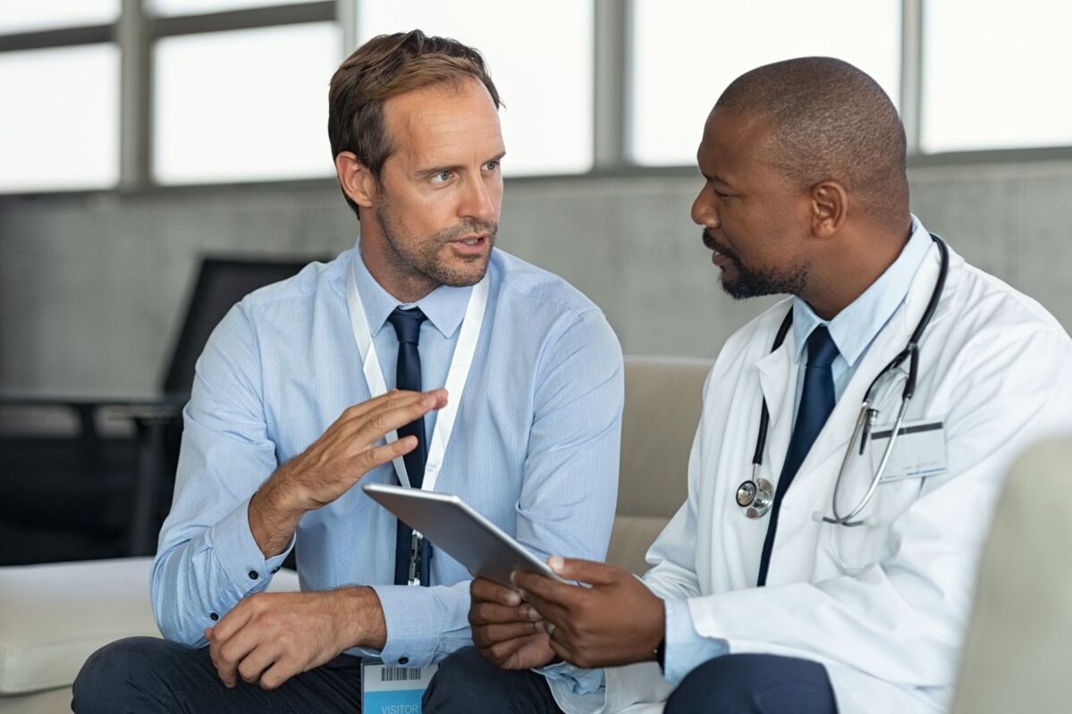 An auditor talking to a doctor in a white coat with a tablet in his hand
