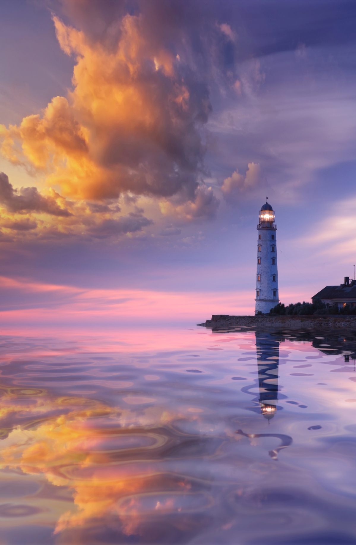 White lighthouse standing on a flat cliff, the play of clouds in the evening sun reflected in the ca