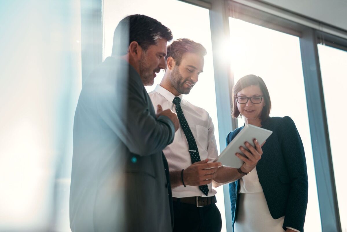 quality-management-dqs-three employees discuss process looking at ipad
